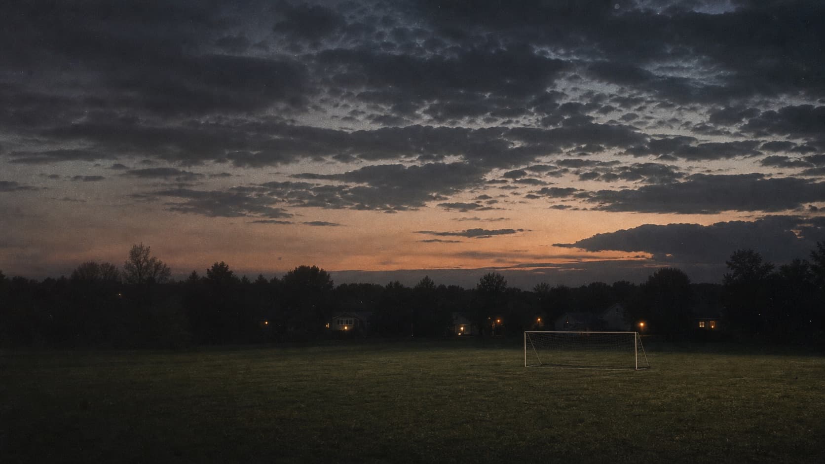 An empty soccer field beneath a wide evening sky