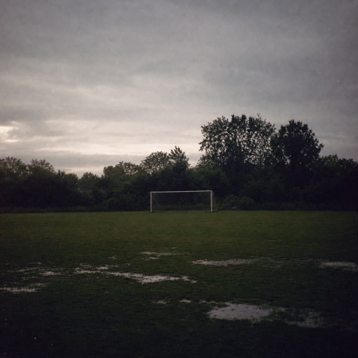A quiet field with a small goal beneath a pale evening sky
